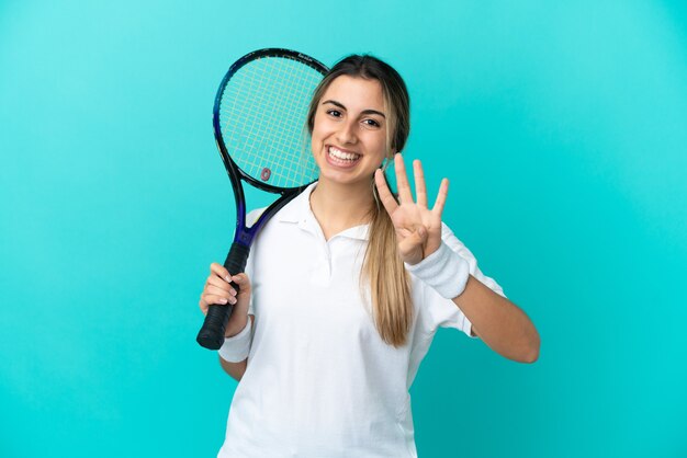 Junge Tennisspielerin isoliert auf blauem Hintergrund glücklich und zählt vier mit den Fingern