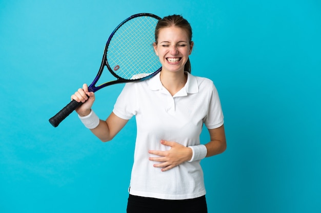 Junge Tennisspielerin lokalisiert auf blauem Hintergrund, der viel lächelt