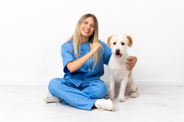 Junge Tierarztfrau mit Hund, der auf dem Boden stolz und selbstzufrieden sitzt