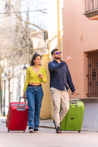 Junge Touristenpaare, die die Straße einer alten Stadt hinuntergehen und mit dem Telefon nach ihrem Hotel suchen