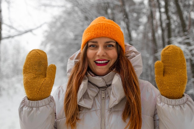 Junge Touristin in warmen Kleidern und gelben Handschuhen macht ein Selfie, während sie in der Stadt im Winter auf dem Berg wandert