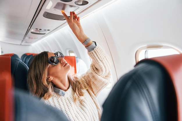 Junge touristische Passagierin in Freizeitkleidung ist im Flugzeug