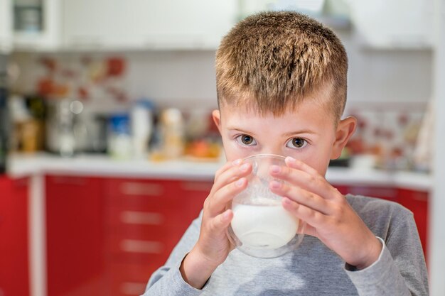 Junge trinkt Milch aus einem Glas in der Küche