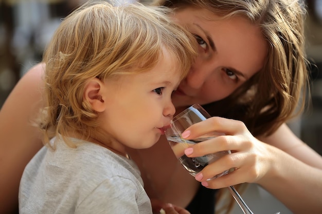 Junge trinkt Wasser mit Mutter