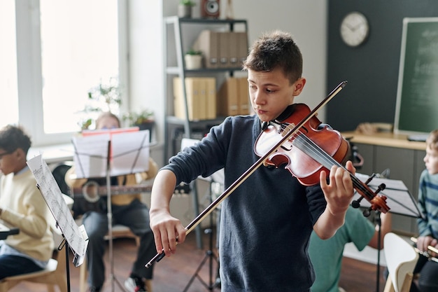 Junge übt Geige im Musikunterricht