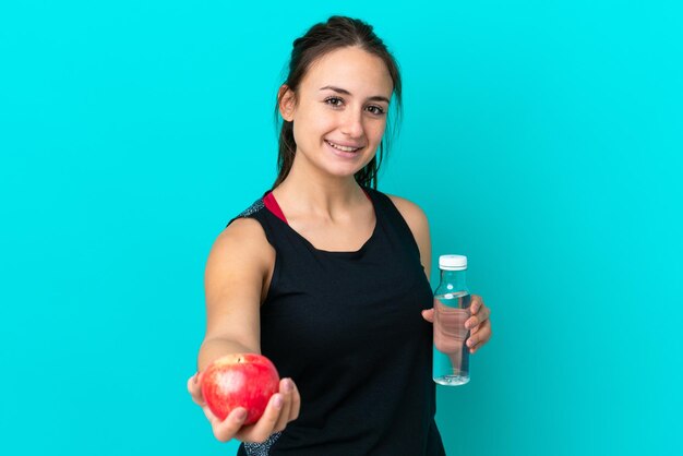 Junge Ukrainerin isoliert auf blauem Hintergrund mit einem Apfel und einer Flasche Wasser