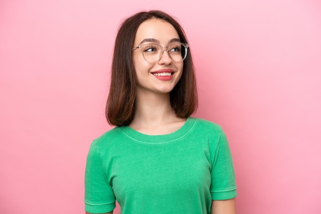 Junge ukrainische Frau isoliert auf rosa Hintergrund mit Brille mit glücklichem Ausdruck