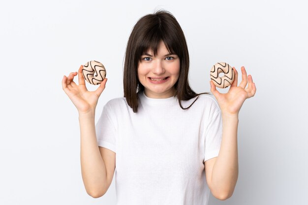 Junge ukrainische Frau lokalisiert auf weißer Wand, die Donuts hält