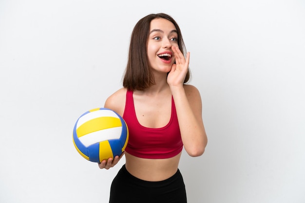 Junge ukrainische Frau spielt Volleyball isoliert auf weißem Hintergrund und schreit mit weit geöffnetem Mund zur Seite