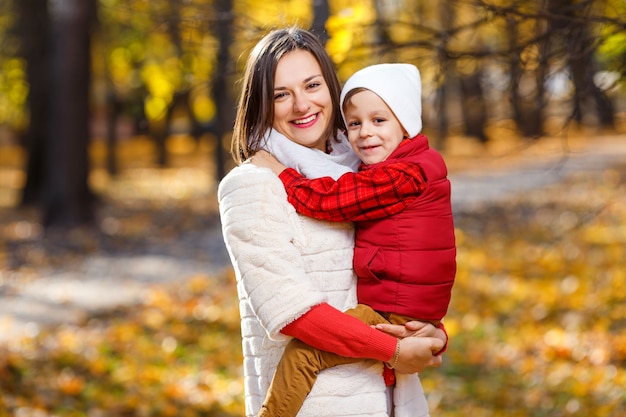 Junge umarmt mit Mutter Kleines Kind hat Spaß mit Mutter im Herbstpark