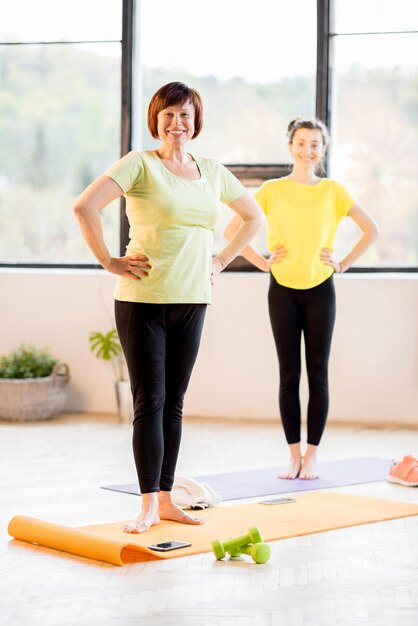 Junge und ältere Frauen in Sportkleidung, die zu Hause oder im Fitnessstudio zusammen Yoga machen