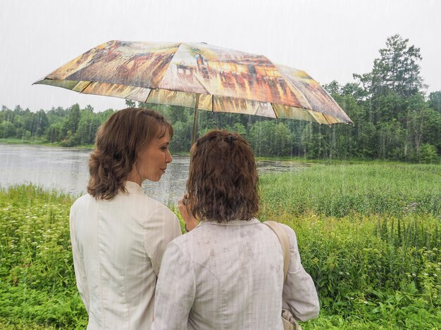 Foto junge und ältere frauen stehen unter einem regenschirm