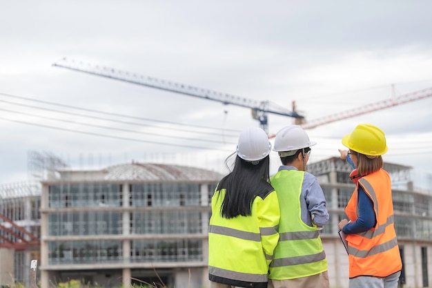 Junge und ältere Ingenieure diskutieren über die Arbeit großer Gebäude im Bau. Drei Personen, die auf der Baustelle des im Bau befindlichen Gebäudes arbeiten