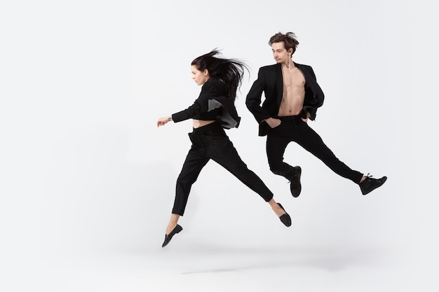 Junge und anmutige Balletttänzer im minimalistischen schwarzen Stil isoliert auf weißem Studiohintergrund