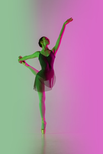 Junge und anmutige Balletttänzerin isoliert auf rosa-grünem Studiohintergrund mit Farbverlauf