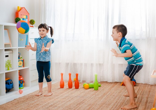 Junge und ein Mädchen spielen mit einem Ball in einem Kinderspielzimmer