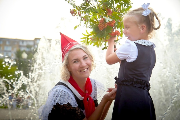 Junge und erwachsene schülerin im september mit blumen amüsieren sich in der nähe von wasserbrunnen generationen von