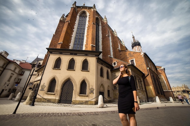 Junge und glückliche Frau Tourist zu Fuß auf dem Marktplatz in der alten europäischen Stadt Krakau Polen reist durch ganz Europa