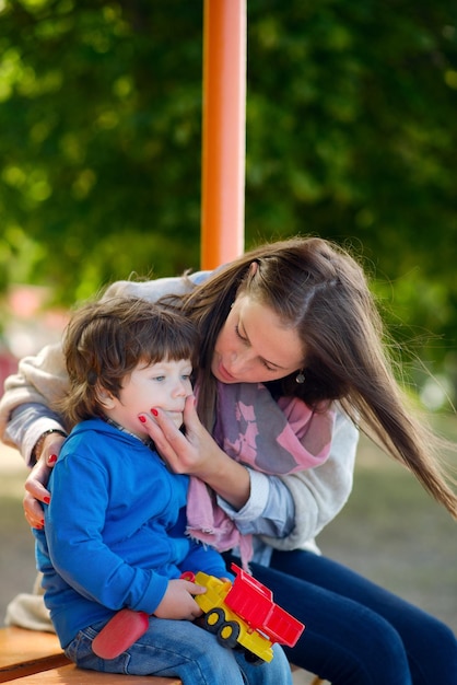 Junge und glückliche Mutter kümmert sich um ihren kleinen Sohn im Sommerpark