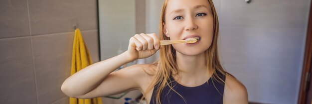 Junge und kaukasische Frau, die ihre Zähne mit einem Bambuszahnbürstenfahnen-Langformat putzt