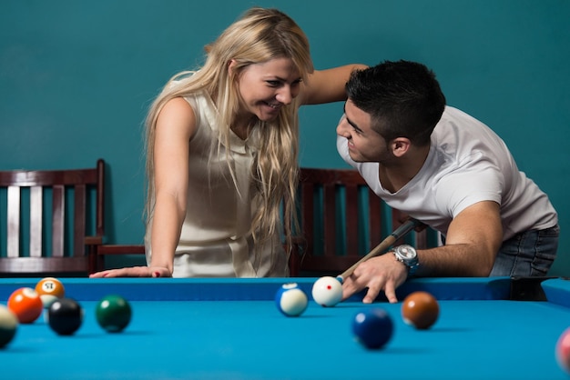 Junge und Mädchen, die auf einem Pool-Spiel flirten