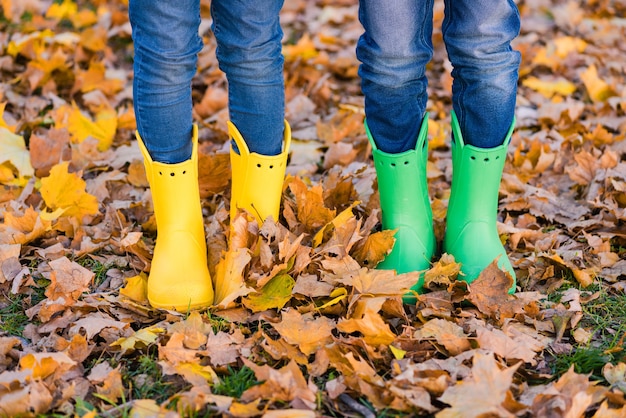 Junge und Mädchen in den gelben und grünen Schuhen im Herbst