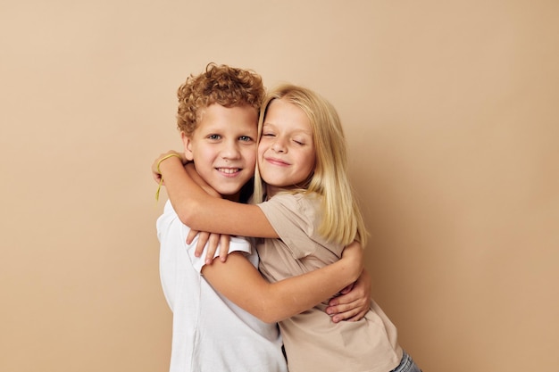 Junge und Mädchen in T-Shirts umarmen beige Hintergrundfreundschaft