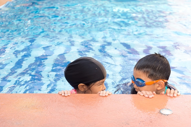 Junge und Mädchen schwimmen im Pool.