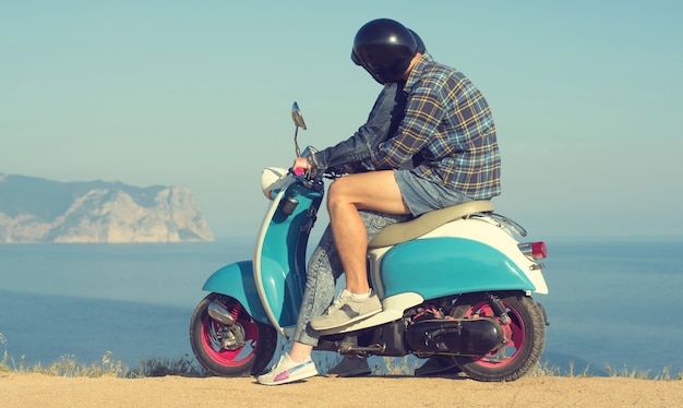 Junge und Mädchen sitzen auf einem Vintage-Motorrad vor dem Hintergrund von Meer und Bergen