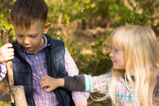 Foto junge und mädchen spielen im herbst zusammen mit stick im freien