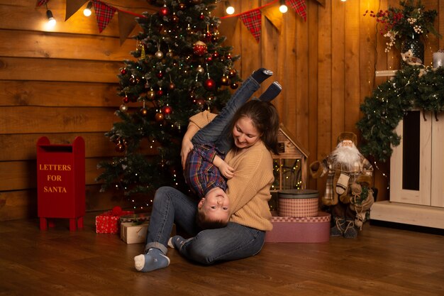 Junge und Mutter spielen nahe Weihnachtsbaum