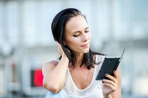 Junge und schöne moderne Geschäftsfrau wirft im Freien mit intelligentem Telefon auf.