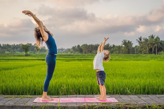 Junge und sein Yogalehrer machen Yoga auf einem Reisfeld