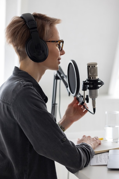 Junge und selbstbewusste europäische Frau, die einen Podcast in einem Tonstudio aufnimmt