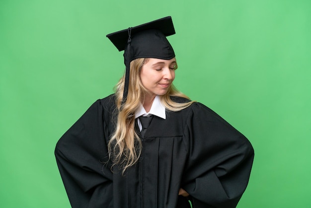 Junge Universitätsabsolventin in Englisch mit isoliertem Hintergrund, die unter Rückenschmerzen leidet, weil sie sich Mühe gegeben hat