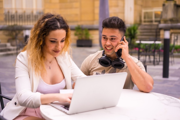 Junge Unternehmer, die Teamarbeit leisten. Arbeiten mit dem Computer auf einer Terrasse einer Bar