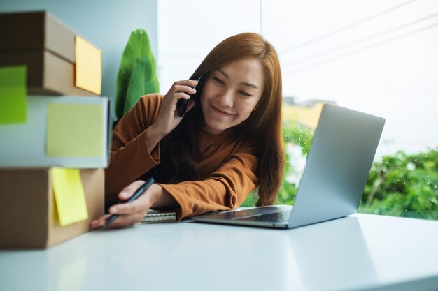 Junge Unternehmerin, die Bestellungen von Kunden am Telefon für Online-Shopping und Lieferkonzept bestätigt und überprüft