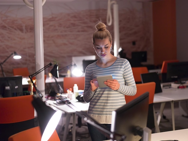 junge Unternehmerin, die im Nachtbüro an einem digitalen Tablet arbeitet