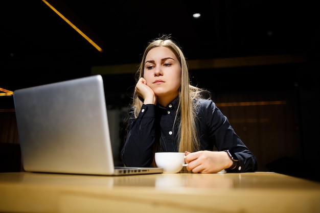 Junge Unternehmerin sitzt am Computer und hat Kopfschmerzen von einem langen Arbeitstag