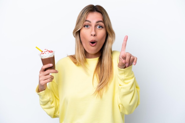 Junge uruguayische Frau, die Frappuccino isoliert auf weißem Hintergrund hält und beabsichtigt, die Lösung zu realisieren, während sie einen Finger hochhebt