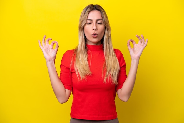 Foto junge uruguayische frau isoliert auf gelbem hintergrund in zen-pose