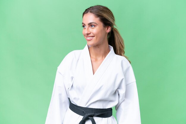 Junge uruguayische Frau macht Karate vor isoliertem Hintergrund, schaut zur Seite und lächelt