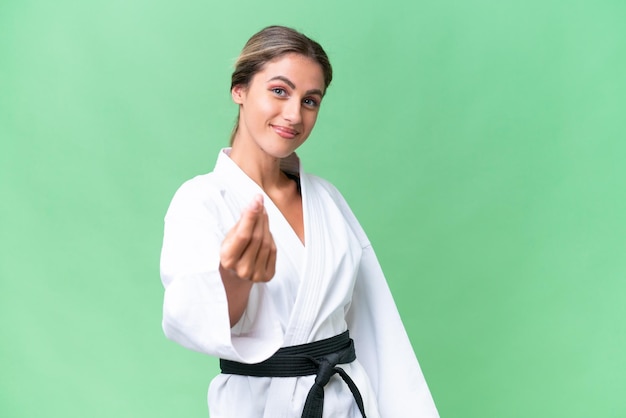 Junge uruguayische Frau macht Karate vor isoliertem Hintergrund und macht Geldgeste