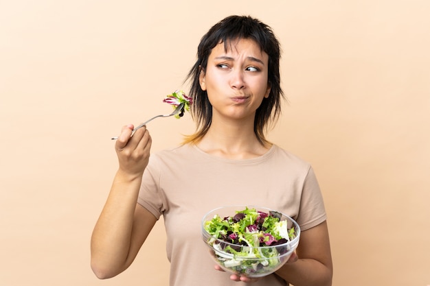 Junge uruguayische Frau mit Salat über Wand