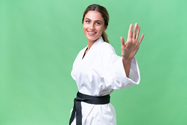 Junge uruguayische Frau vor isoliertem Hintergrund, die mit glücklichem Gesichtsausdruck mit der Hand salutiert