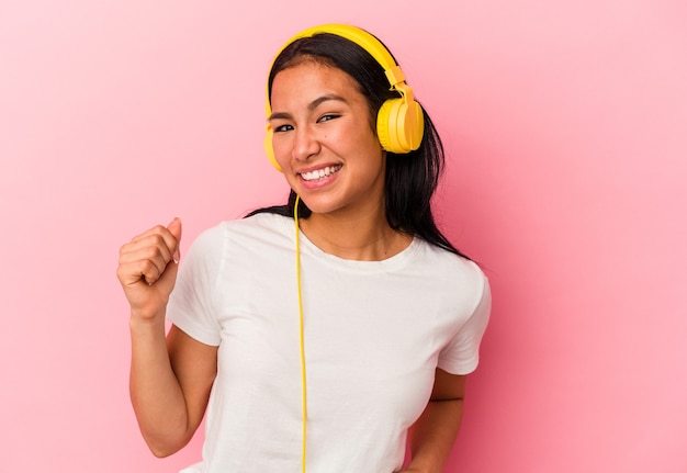 Junge venezolanische Frau hört Musik isoliert auf rosa Hintergrund