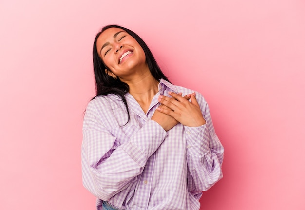 Junge venezolanische Frau isoliert auf rosa Hintergrund lachend die Hände am Herzen halten, Konzept des Glücks