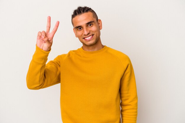 Junge venezolanische Mann isoliert auf weißer Wand fröhlich und sorglos zeigt ein Friedenssymbol mit den Fingern.