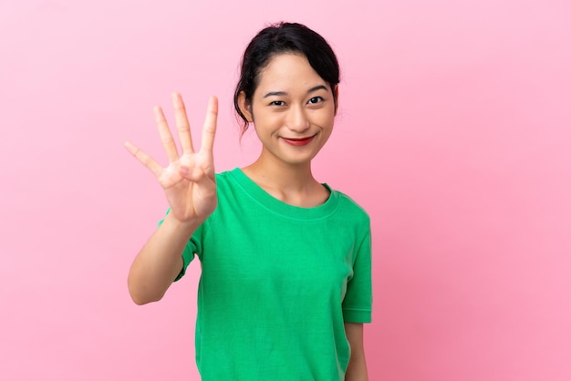 Junge Vietnamesin isoliert auf rosa Hintergrund glücklich und zählt vier mit den Fingern