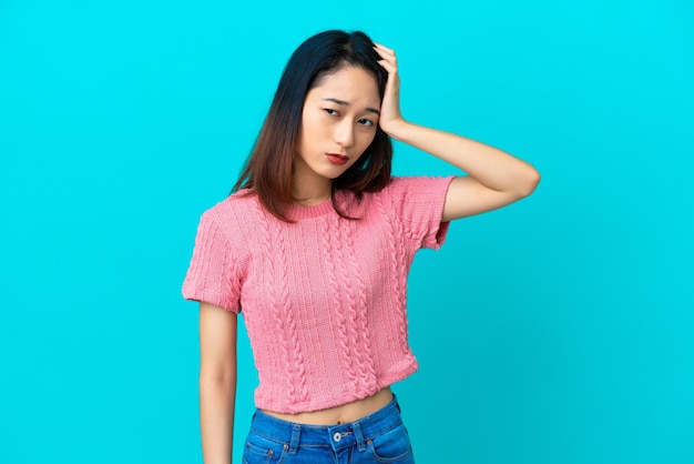 Junge vietnamesische Frau isoliert auf blauem Hintergrund mit einem Ausdruck von Frustration und Unverständnis